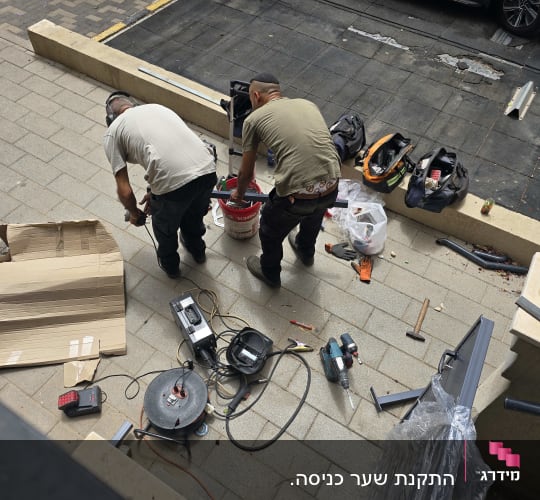 שני אנשים עובדים עם כלים ליד מסגרת מתכת